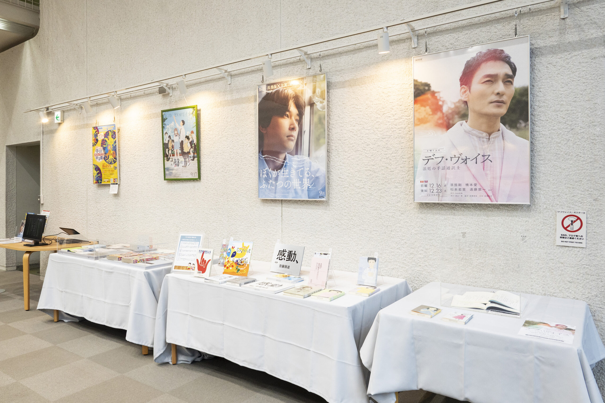 ポスターが飾られ、冊子や本が展示されている写真