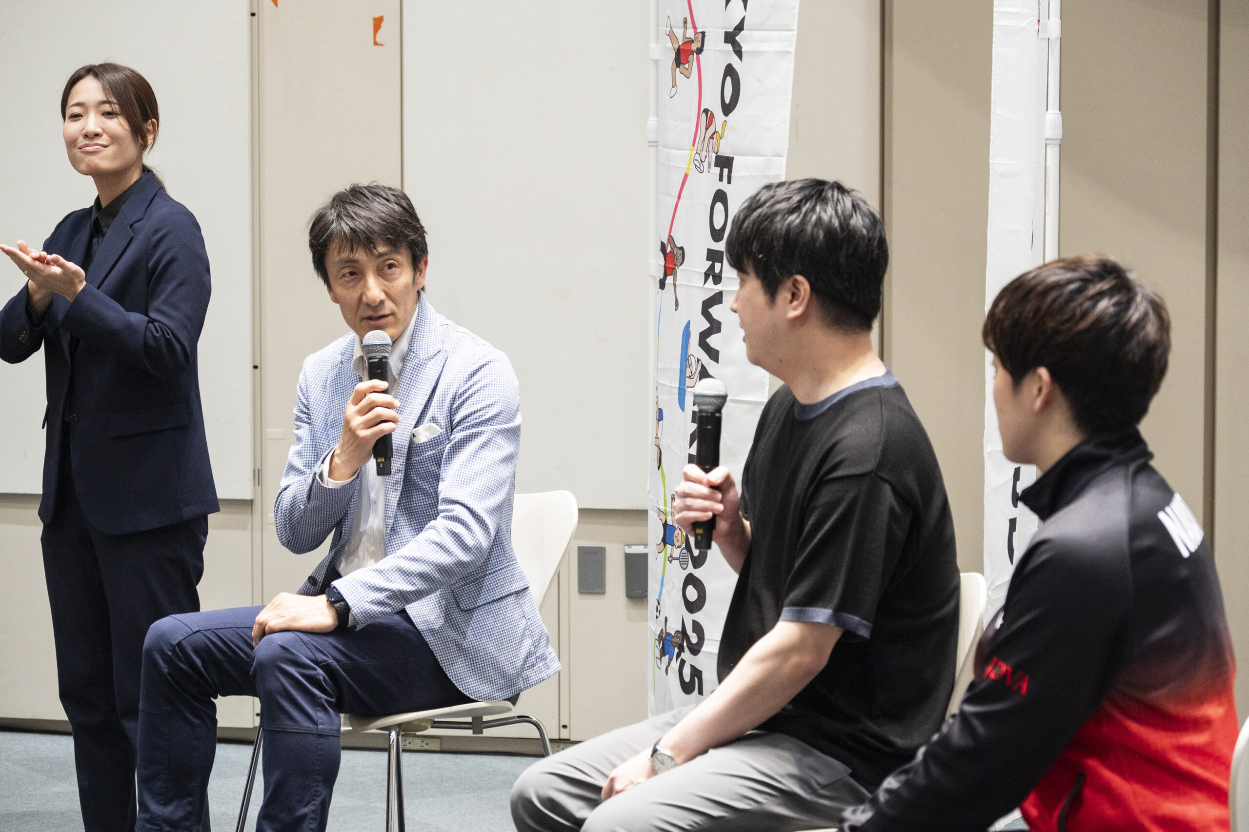 朝原さんが五十嵐さんと中田選手を見ながらマイクを持って話をしている写真