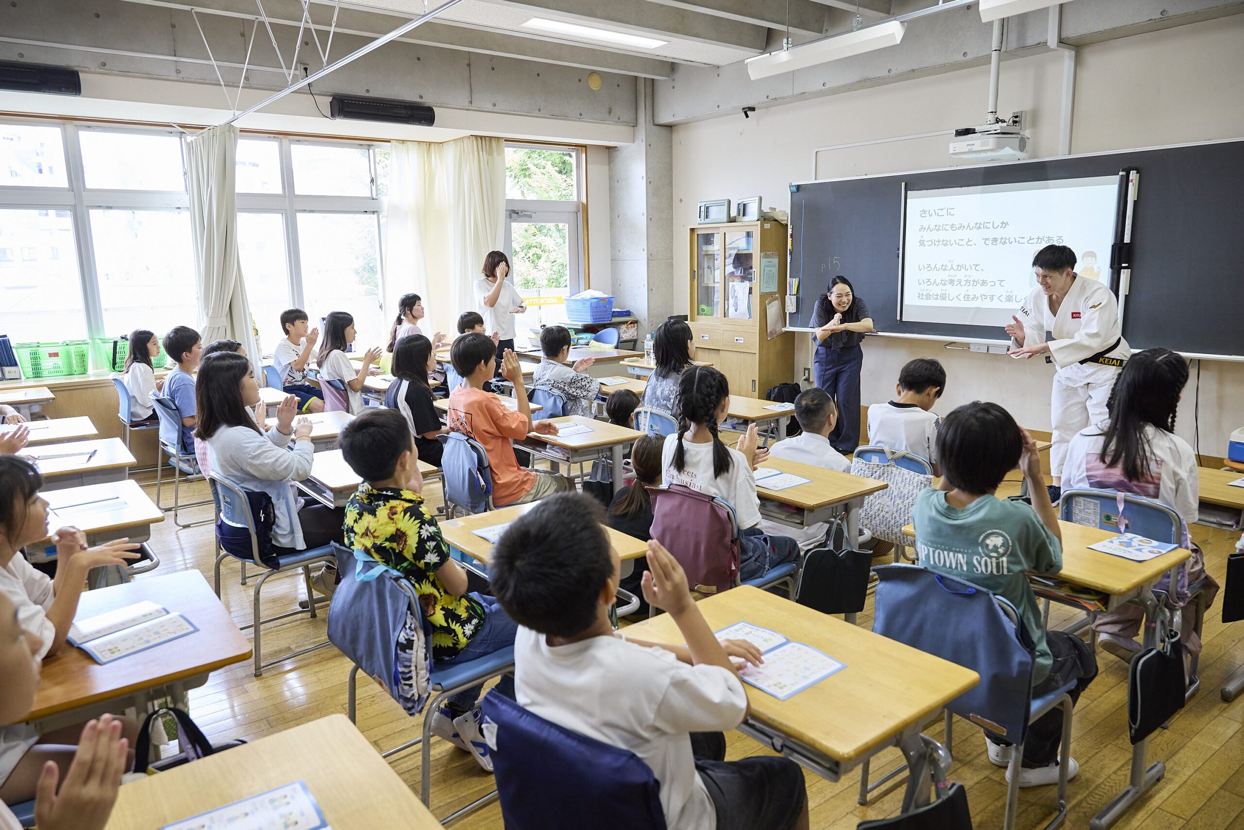 児童と一緒にありがとうの手話をしている川俣さんと佐藤選手の写真