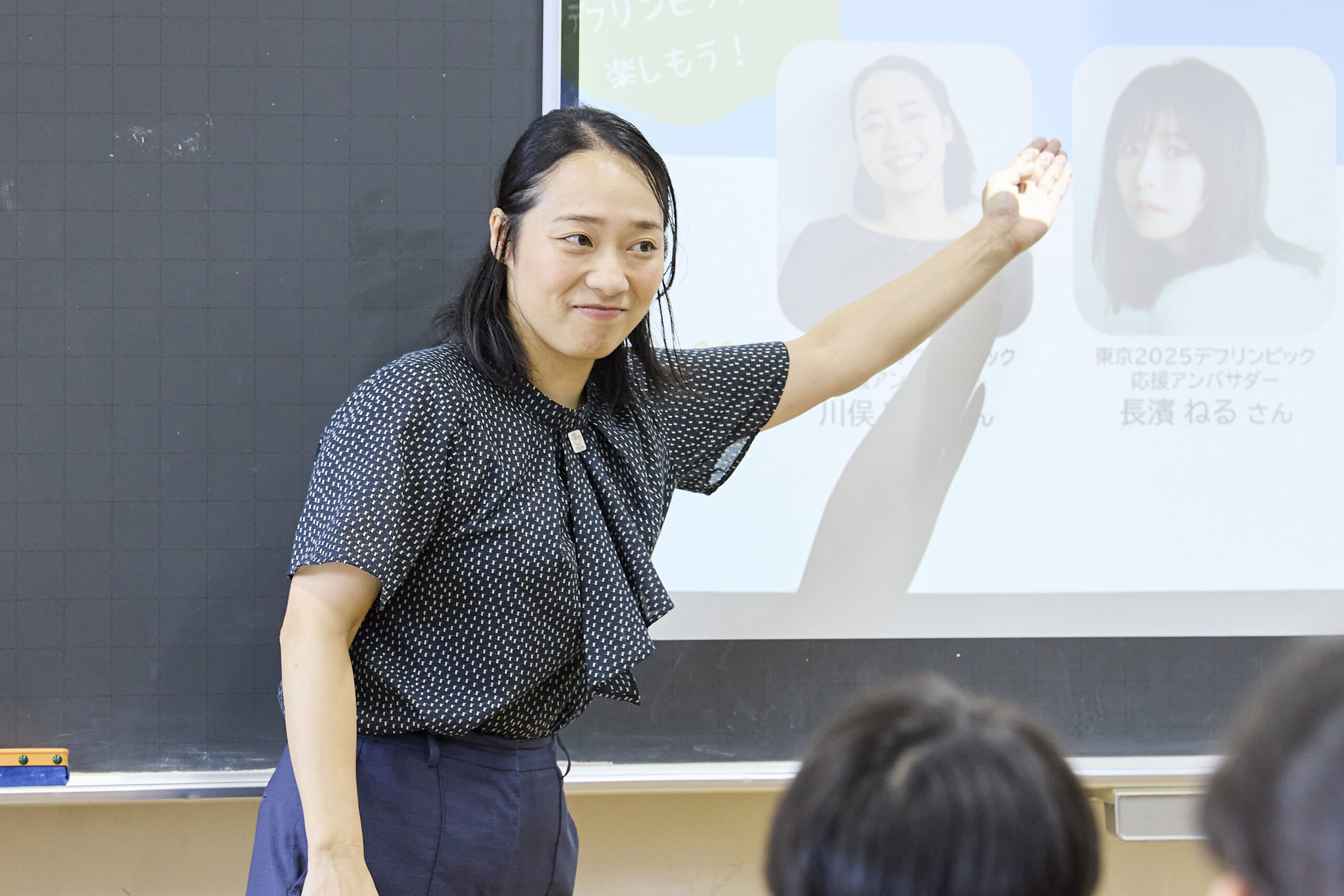 左手でスクリーンを指している川俣さんの写真