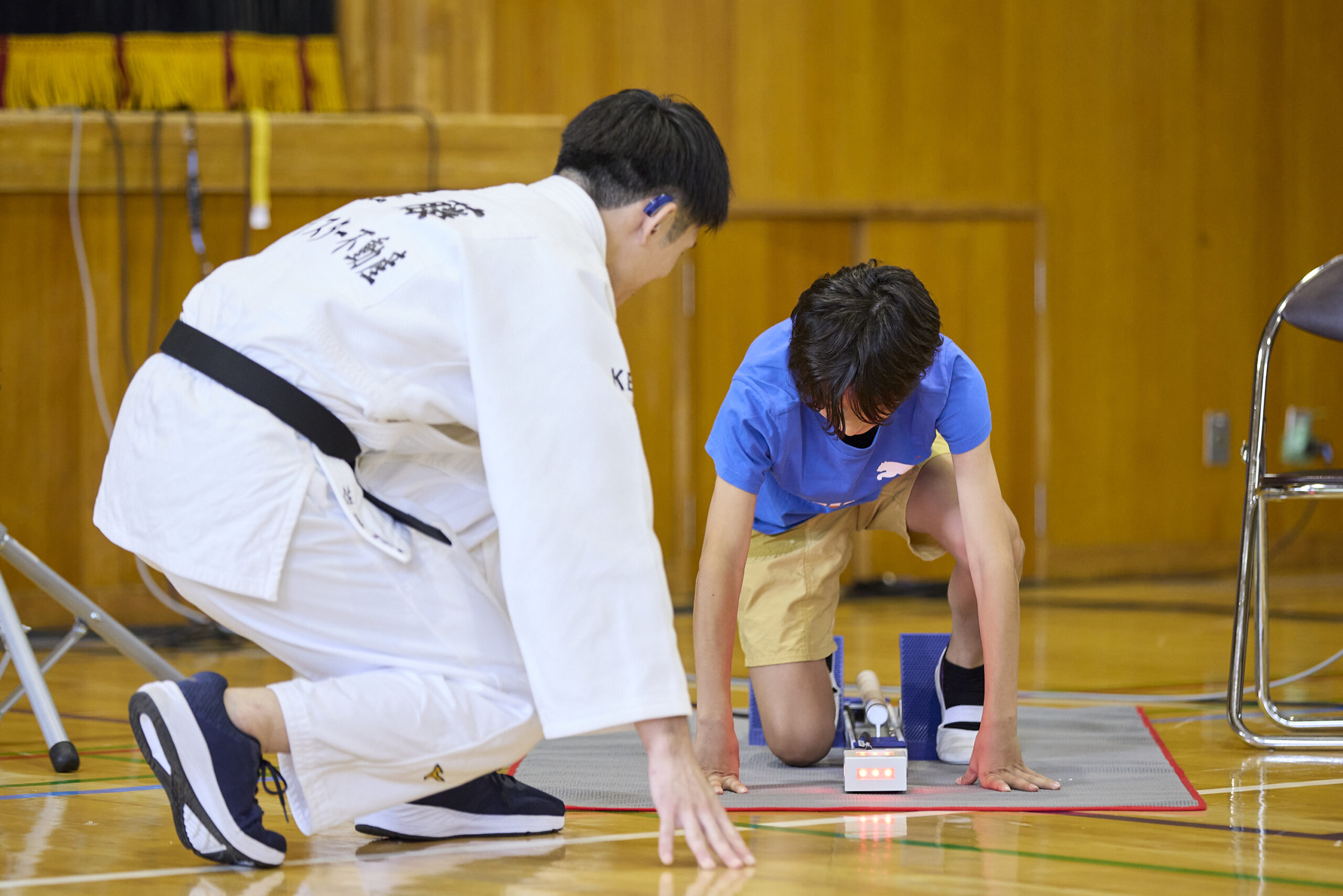 クラウチングスタートをしている児童とその横にいる佐藤選手の写真
