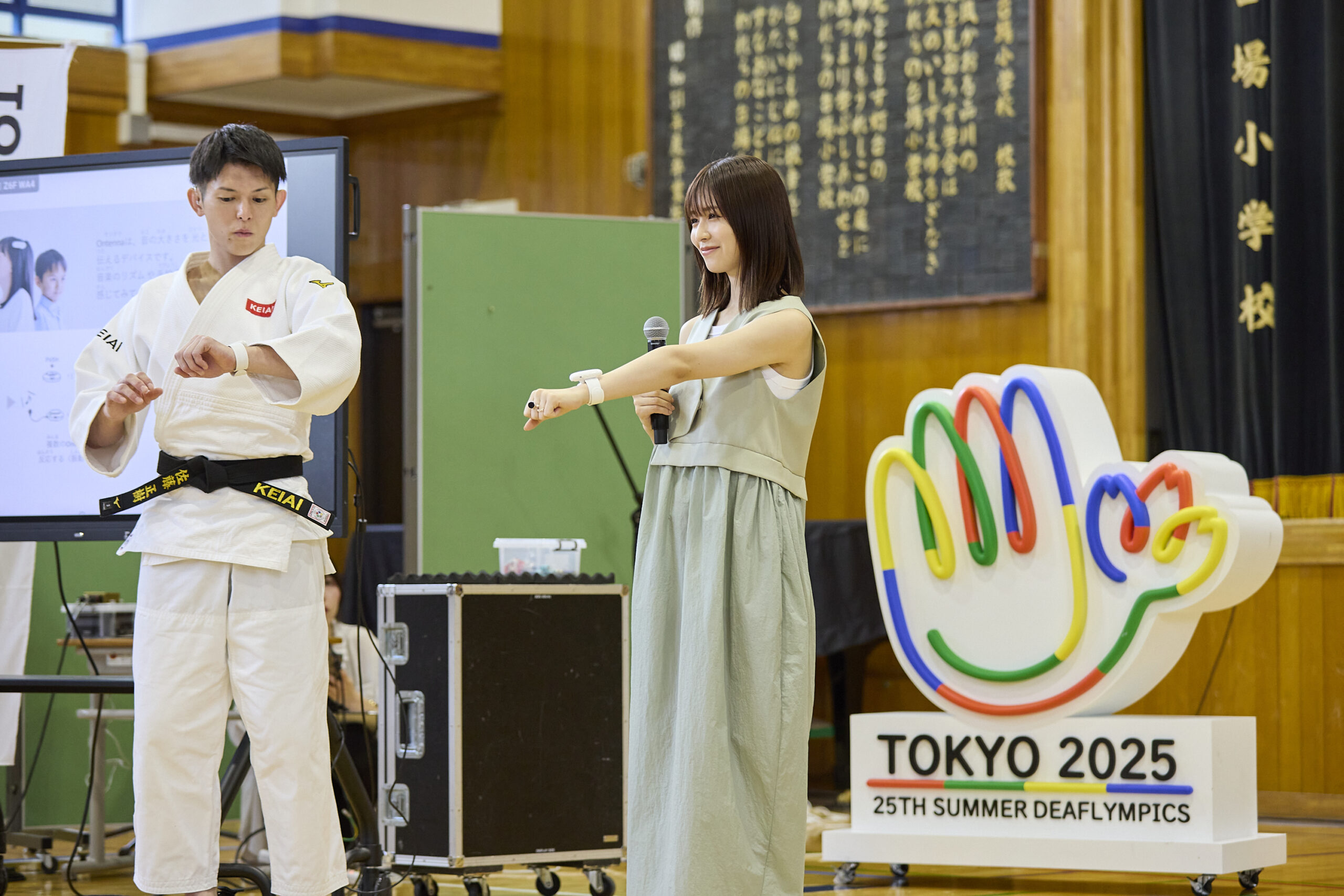 左腕にOnntenaを付け見つめている佐藤選手と児童に見せている長濱さんの写真