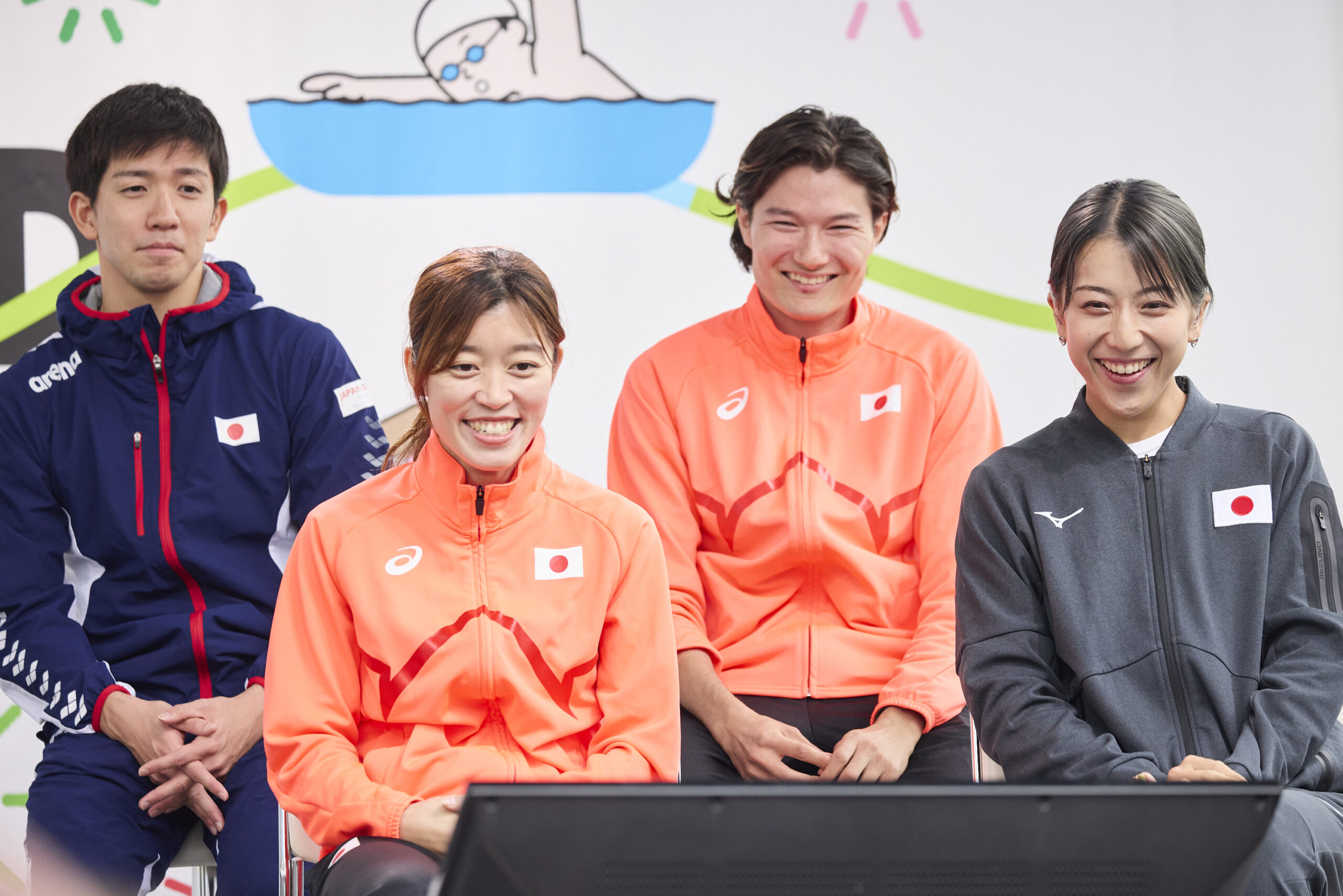 前列に岡田選手と亀澤選手、後列に茨選手と山田選手が座り、前にあるモニターを観ている写真