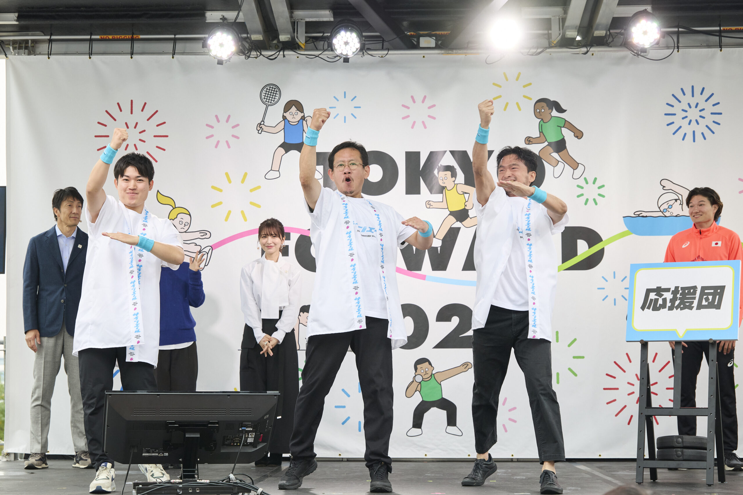 制作者の3名がガッツポーズをしてサインエールをやっている写真