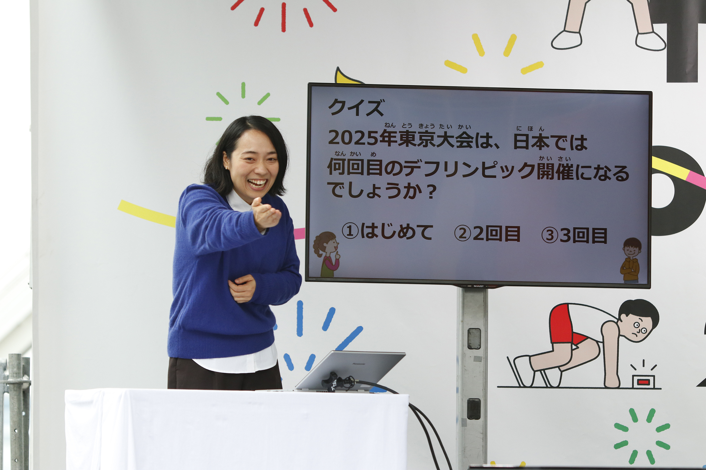 壇上から川俣さんが誰かを指している写真