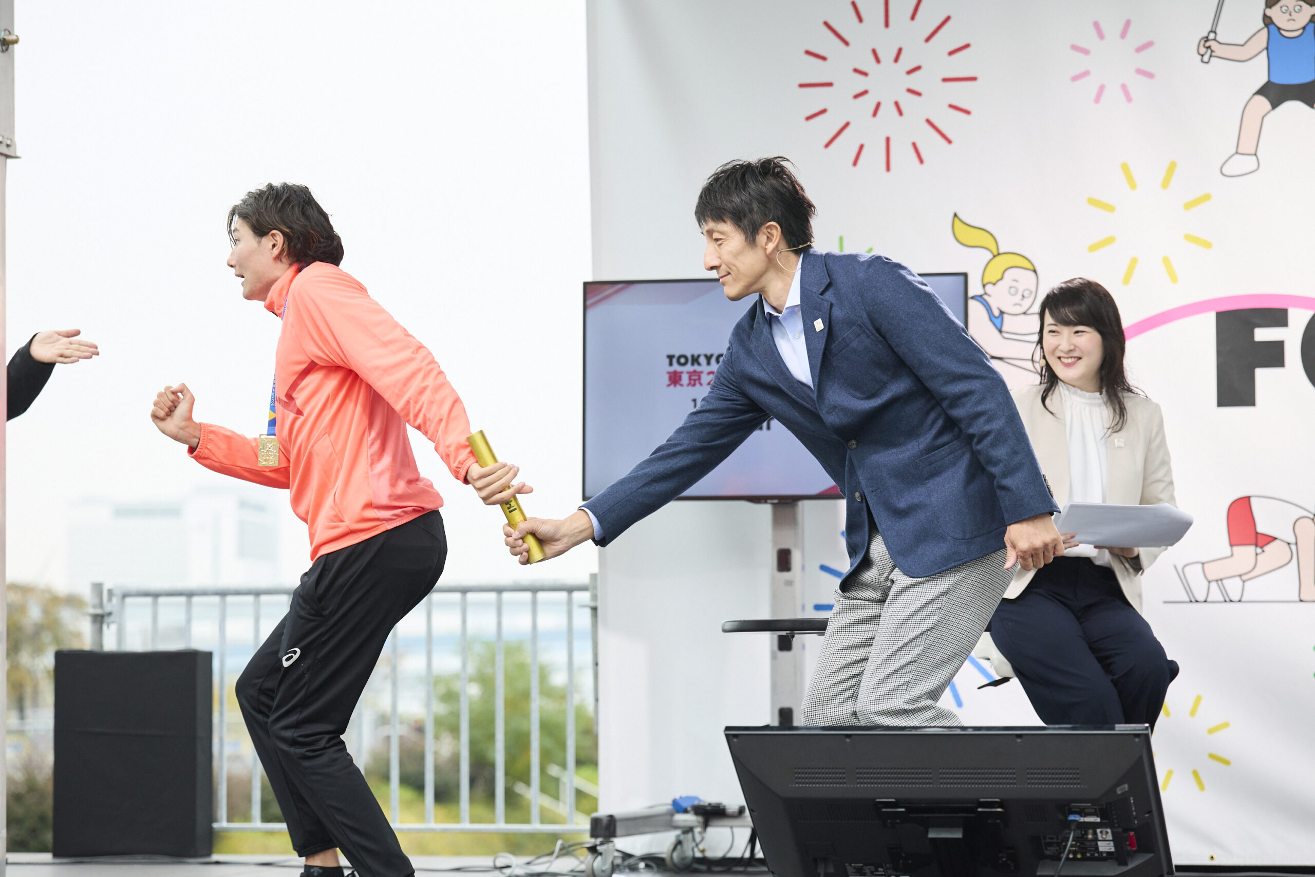 山田選手の手にバトンが渡り朝原さんが手を離そうとしている写真