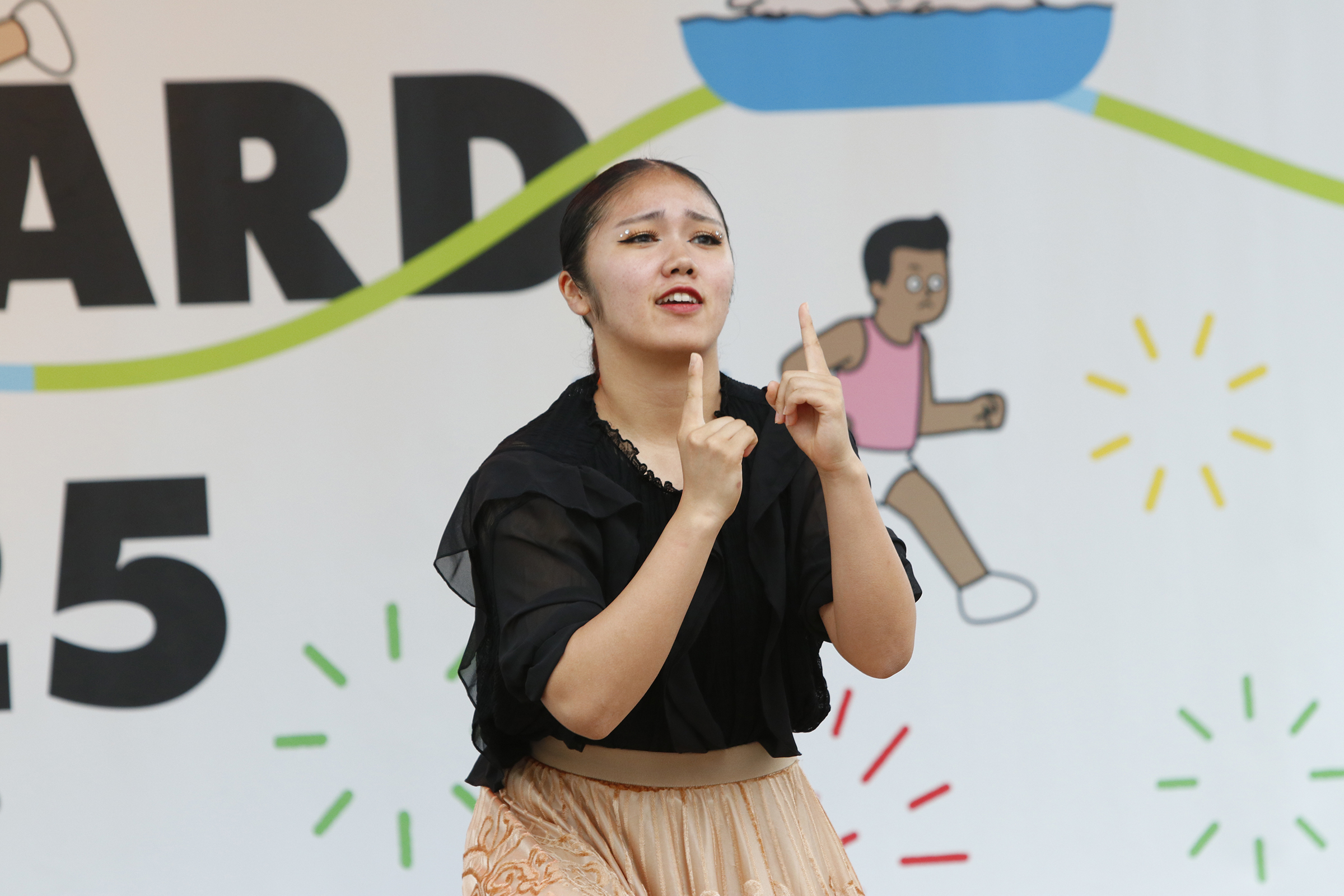 パフォーマーが両人差し指を立てて手話をしている写真