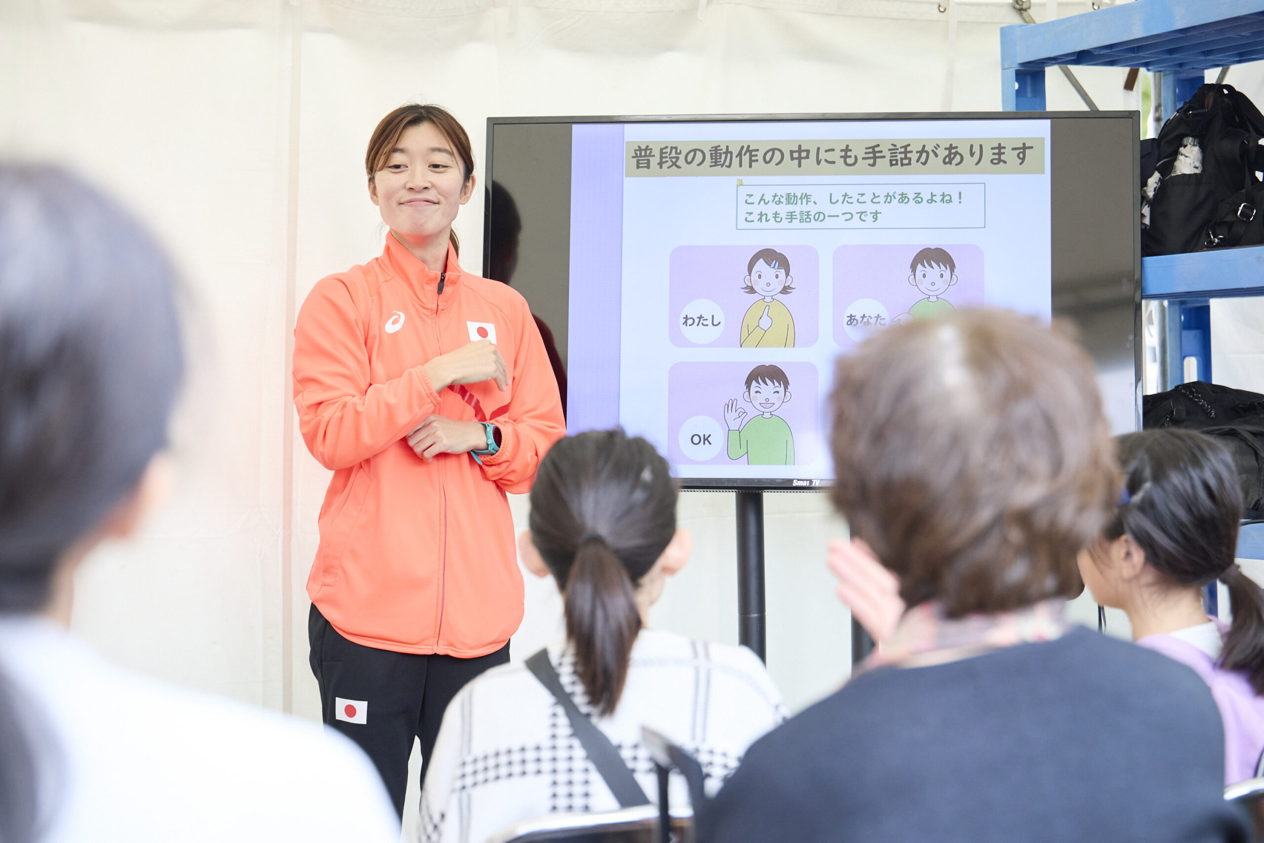 岡田選手がモニターの横で説明している写真